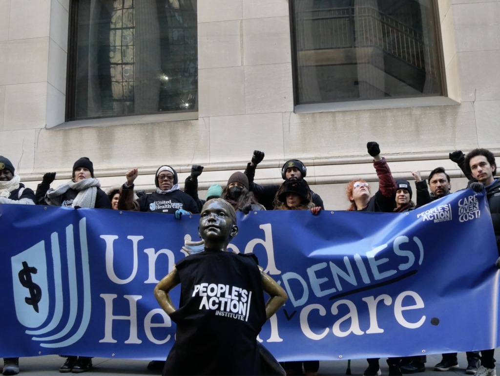 Photo of protesters in front of Wall Street Girl statue weather People's Action shirt